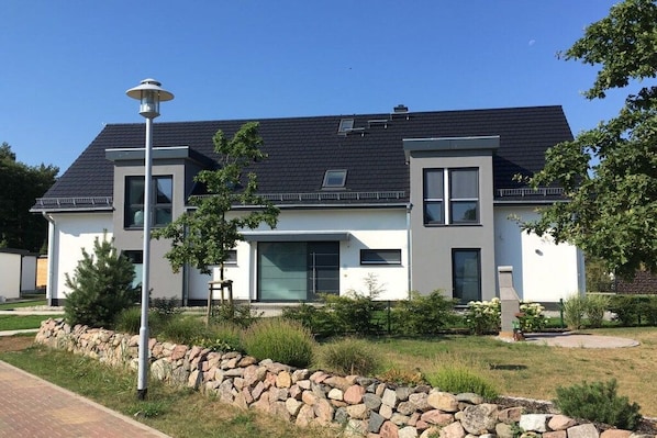 Ett modernt hus i två våningar med en stenmur och en asfalterad uppfart.