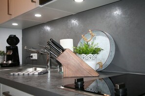 A kitchen counter with a coffee machine, a knife block, and a potted plant. - Alpenflair Holiday Apartment 106 (Oberstdorf)