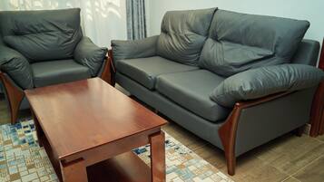 Un salon comprenant un canapé, deux fauteuils et une table basse en bois.
