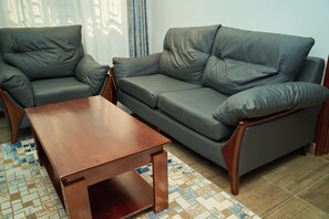 Una sala de estar con un sofá, dos sillones y una mesa de centro de madera.
