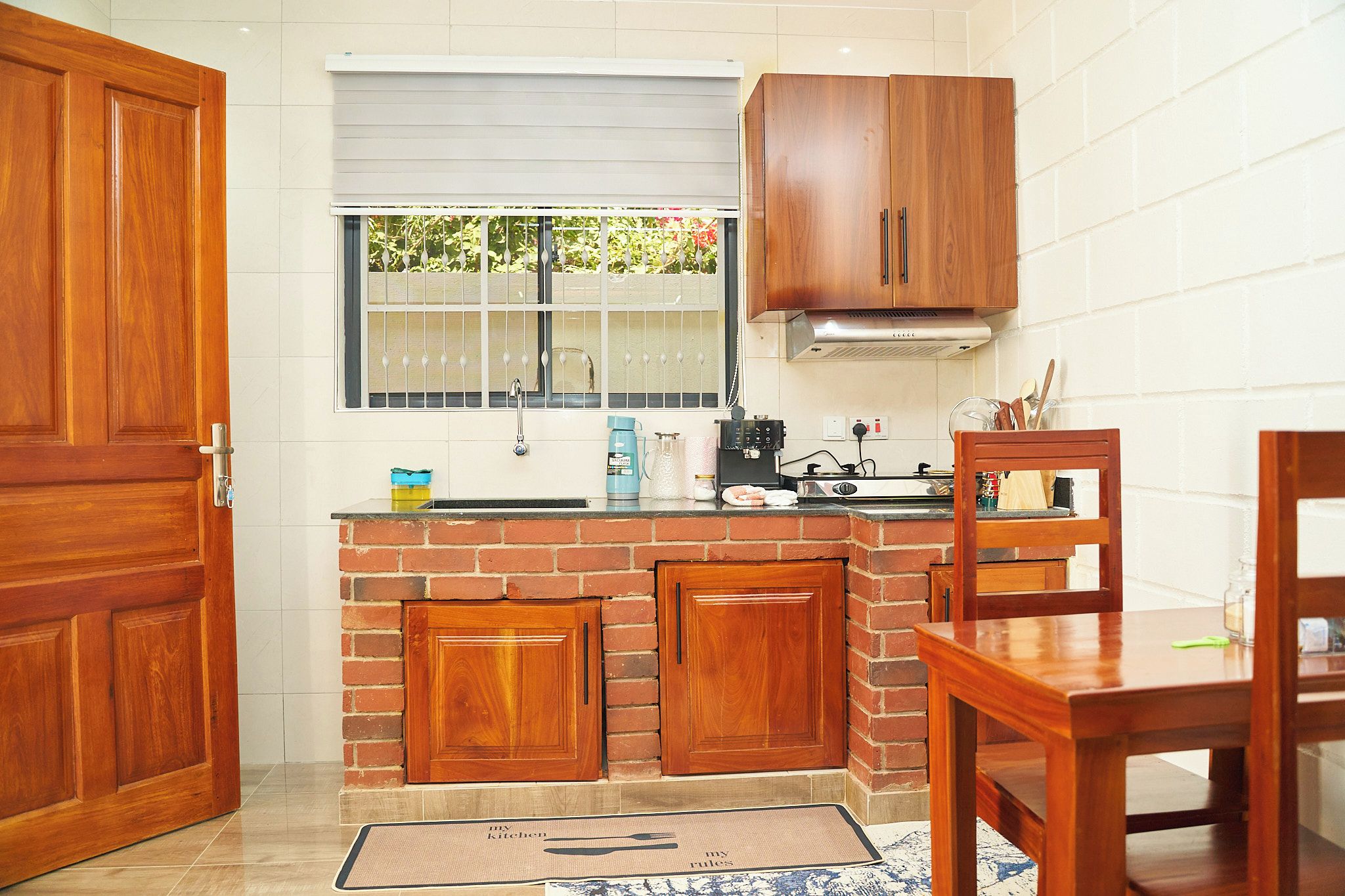 Une cuisine compacte avec des meubles en bois, une cuisinière à gaz et une fenêtre donnant sur un jardin.