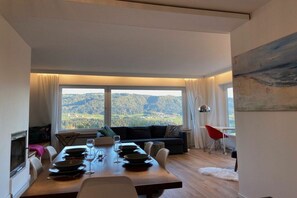 A dining area with a view of the countryside, a sofa, and a red chair. - Holiday apartment with 1 bedroom (Sigmarszell)