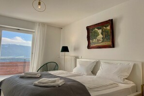 A hotel room with a bed, a painting, a lamp, and a view of the outdoors. - Holiday apartment with 1 bedroom (Sigmarszell)