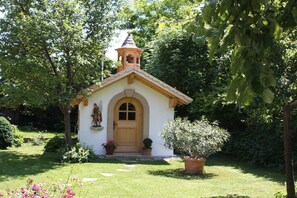 En lille kirke med et klokketårn, en buet indgang og en statue.