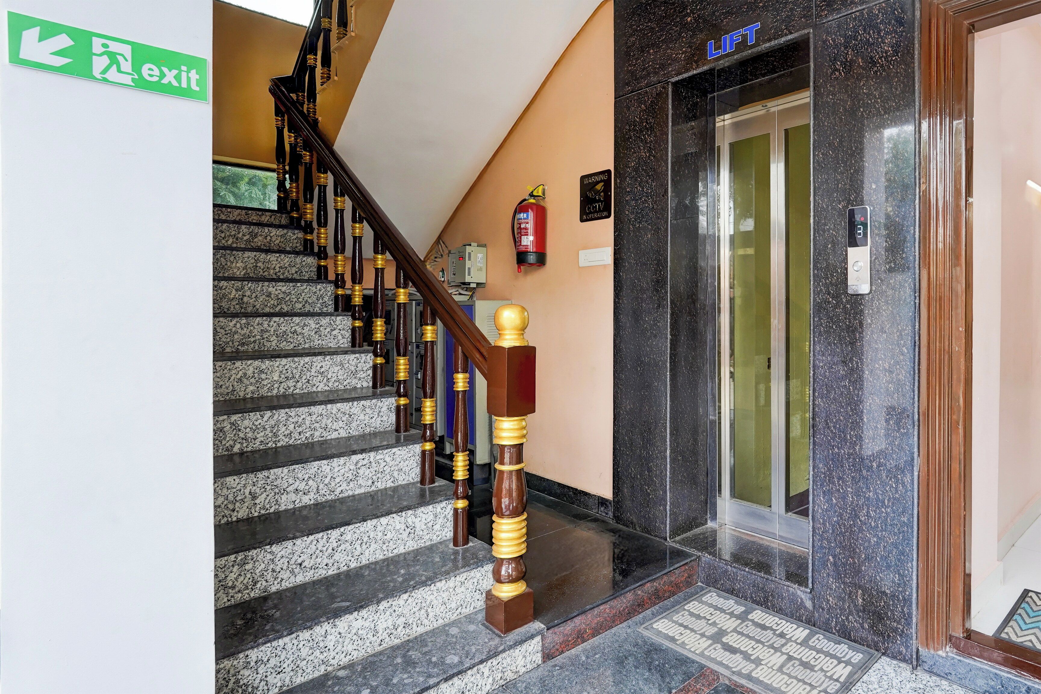 A staircase with a wooden handrail and a fire extinguisher mounted on the wall.