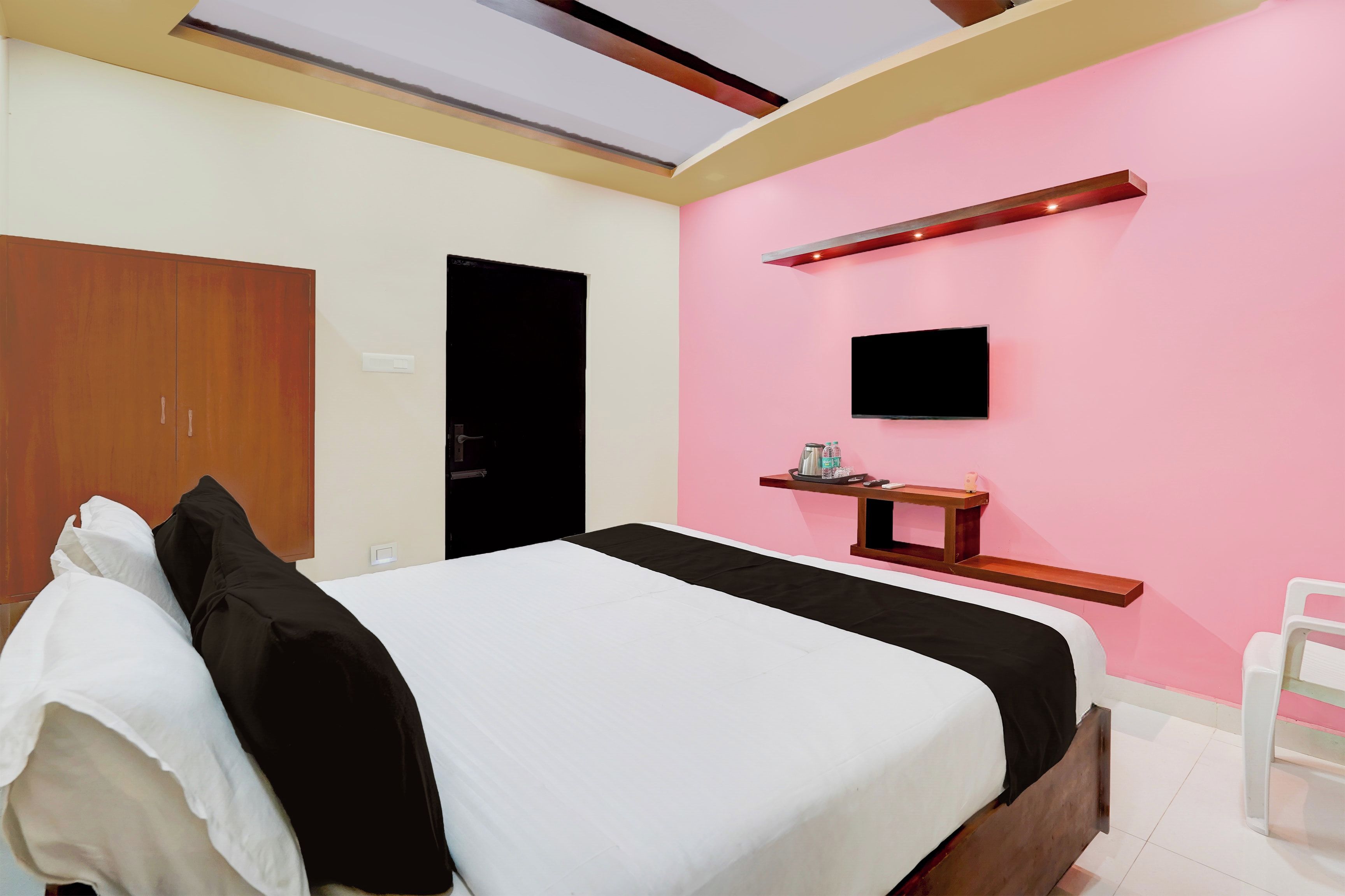 A bedroom with a bed, a wardrobe, a television, and a shelf with items.