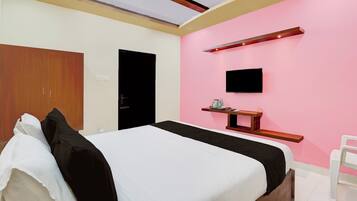 A bedroom with a bed, a wardrobe, a television, and a shelf with items.