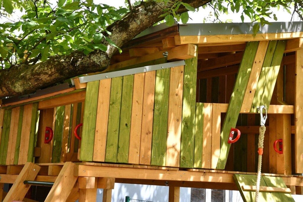 A wooden structure with a rope ladder and red handles, likely a birdhouse or a children's playhouse.