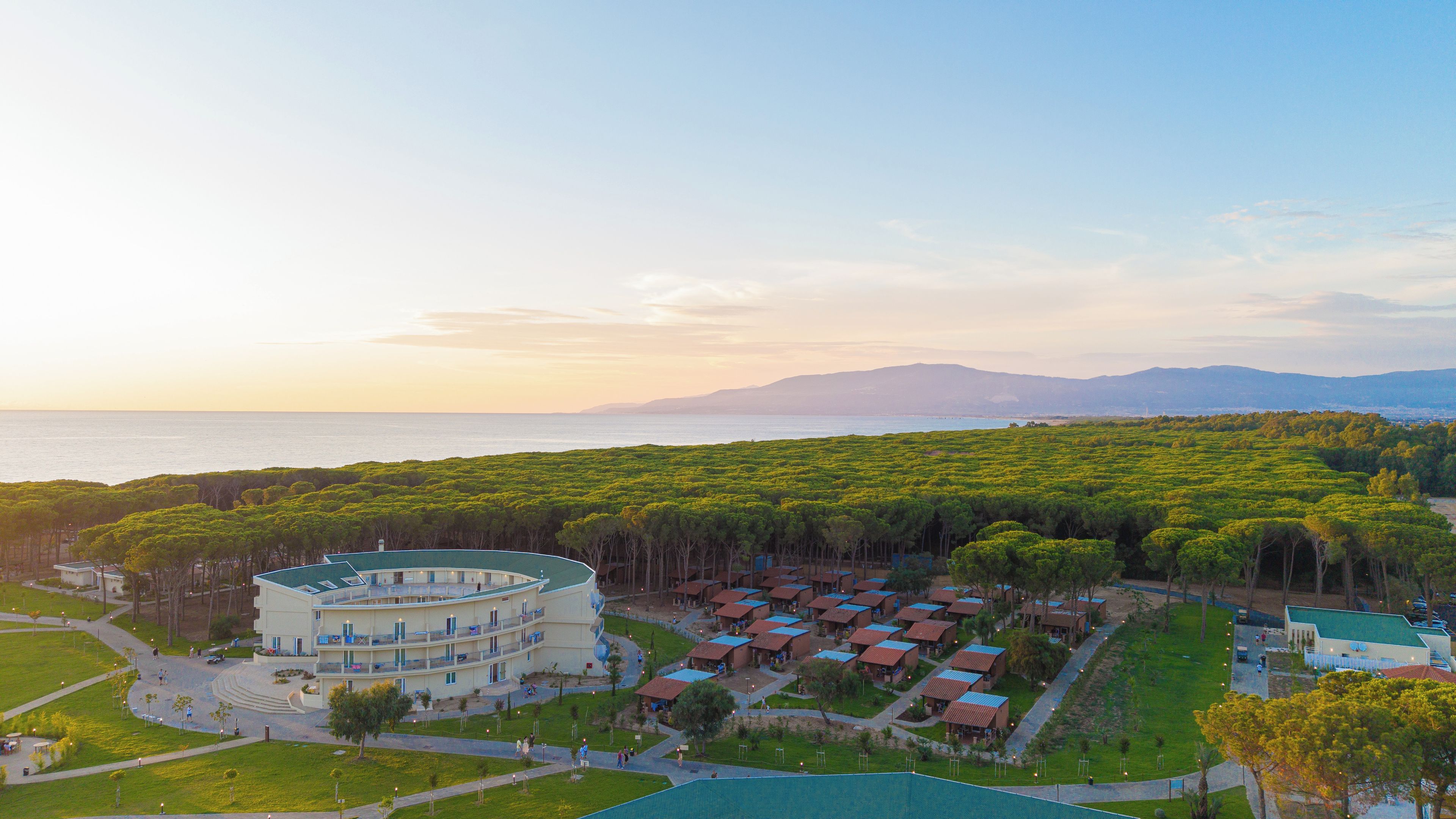 A resort with multiple buildings, a pool, and a view of the sea.