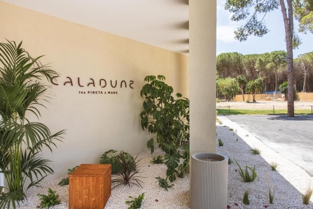 Ein Gebäudefassaden mit der Aufschrift 'Caladune' und dem Schriftzug 'tra pineta e mare', der auf einen Bezug zu einem Pinienwald und dem Meer hinweist.