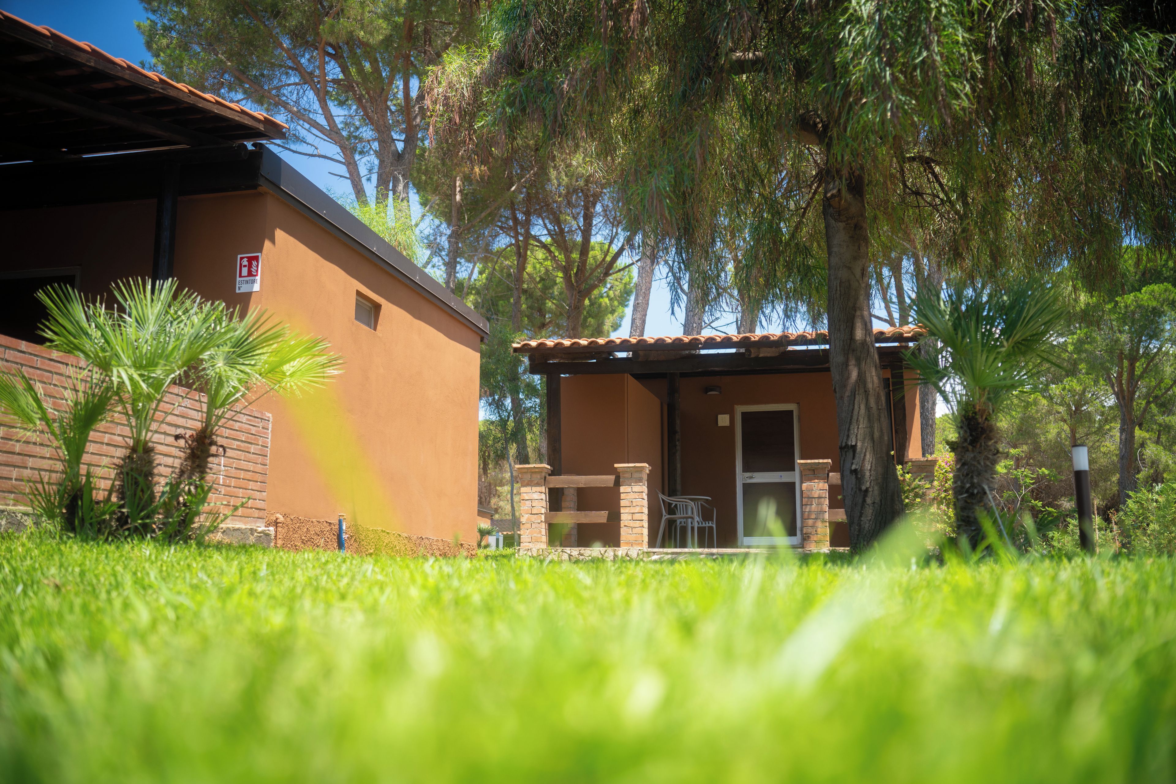 A building with a brick facade, a tiled roof, and a small patio area with a chair.
