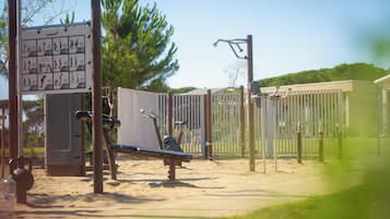 An outdoor exercise area with a bench, exercise equipment, and a sign with instructions.