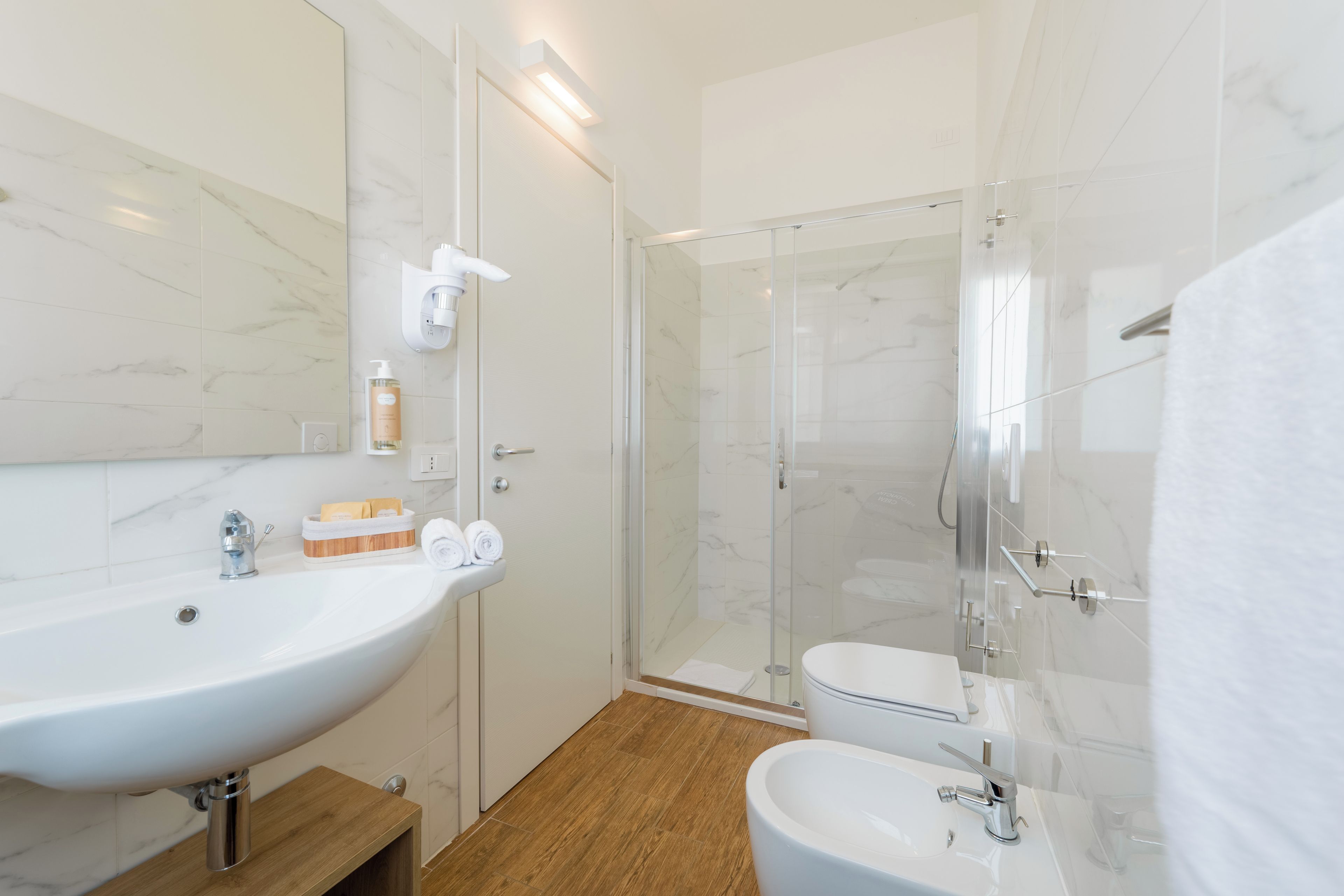Un baño moderno con un lavamanos grande de color blanco, una ducha con cerramiento de vidrio y un inodoro.