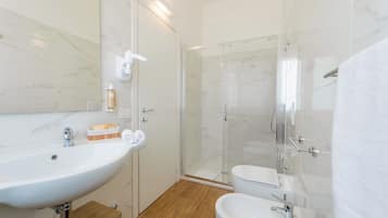 Un baño moderno con un lavamanos grande de color blanco, una ducha con cerramiento de vidrio y un inodoro.