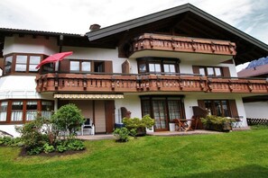 A two-story building with a balcony, a covered porch, and a well-maintained lawn. - Alpenflair holiday apartment 201 (Oberstdorf)