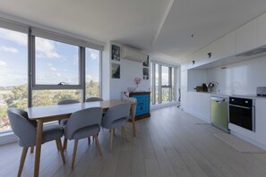 Eine moderne Küche mit weißen Schränken, einer blauen Akzentwand und großen Fenstern mit Blick auf die Stadt.