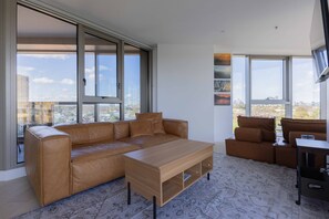 Ein modernes Wohnzimmer mit einer Ledersofa, einem Holztisch und einem an der Wand befestigten Fernseher.