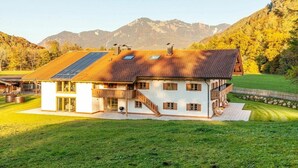 Une maison à deux étages, dotée d’un toit en pente, de grandes fenêtres et d’un balcon.