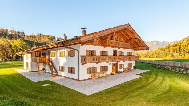 Un chalet à deux étages, doté d’un toit en pente, de balcons en bois et de fondations en pierre.