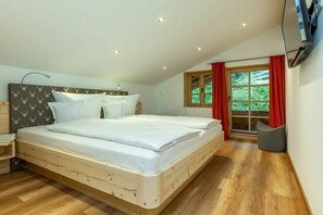 Una camera da letto con un letto in legno, un comodino, una finestra con tende e una TV a parete.