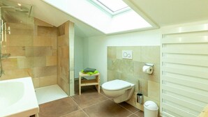 Une petite salle de bain dotée d’un puits de lumière, d’une douche, de toilettes et d’un lavabo.