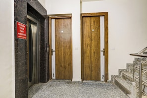 Un passadís amb dues portes de fusta, una amb un cartell que indica que no es permet menjar d'en fora, i una escala amb baranes metàl·liques.