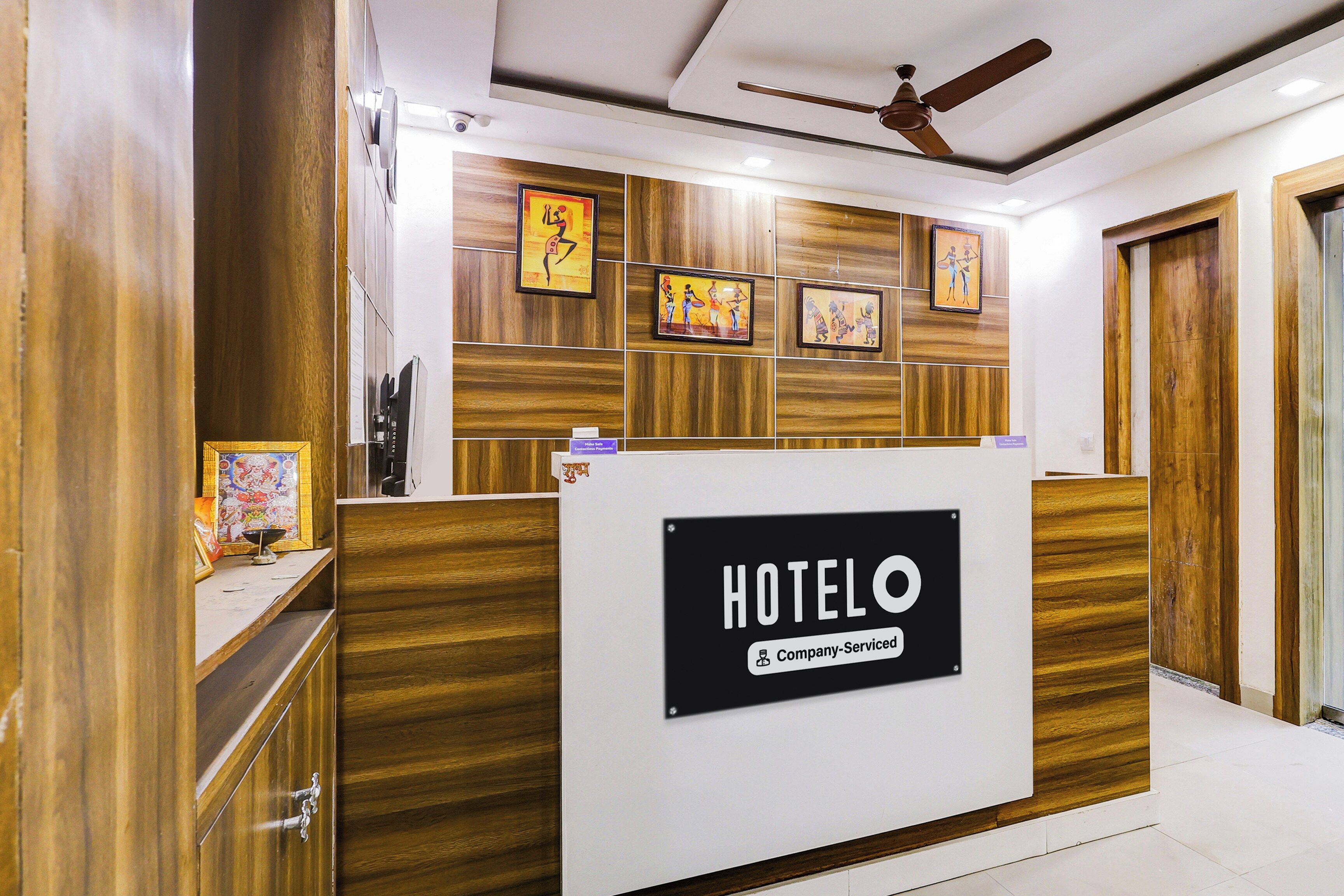 Ein Hotelrezeptionstresen mit einem 'HOTELO'-Schild, Holzvertäfelung und gerahmten Bildern an der Wand.