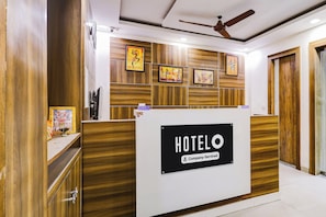 Un taulell de recepció d'hotel amb un cartell de 'HOTELO', panells de fusta i una obra d'art emmarcada a la paret.