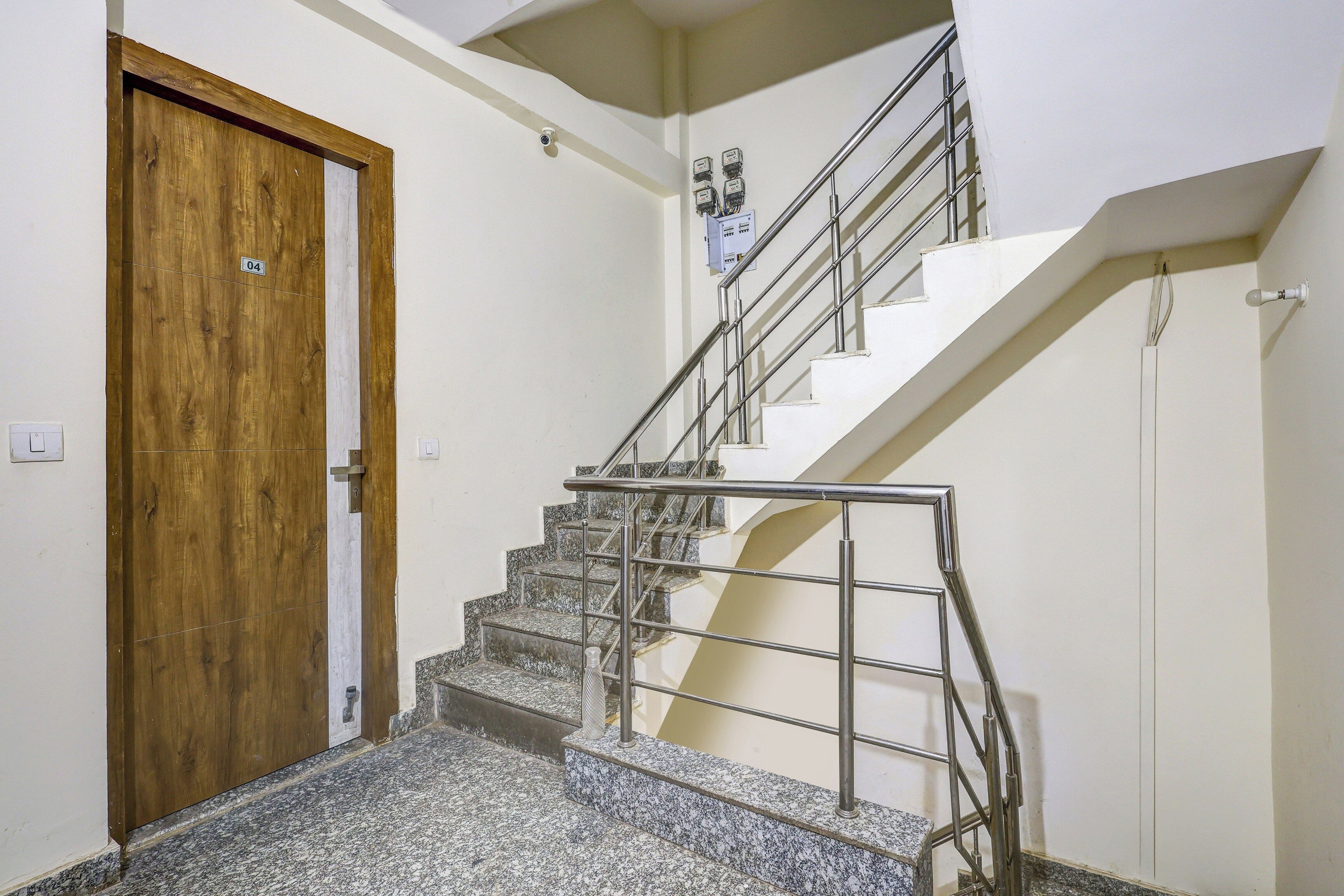 A staircase with metal railings and a wooden door with a number plate.