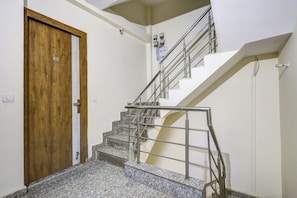 Un escalier avec des rampes en métal et une porte en bois portant une plaque avec un numéro.
