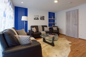 A modern living room with a leather sofa, a glass coffee table, and a shaggy rug. - Aquamarine Suite KURFÜRST KARL THEODOR (Oberstdorf)