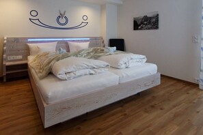 Une chambre à coucher avec un lit, des tables de chevet, une lampe fixée au mur et un tableau encadré.