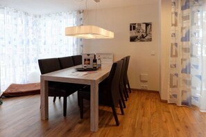 A dining area with a wooden table, black chairs, a hanging light fixture, and a framed picture on the wall. - Aquamarine Suite KURFÜRST KARL THEODOR (Oberstdorf)