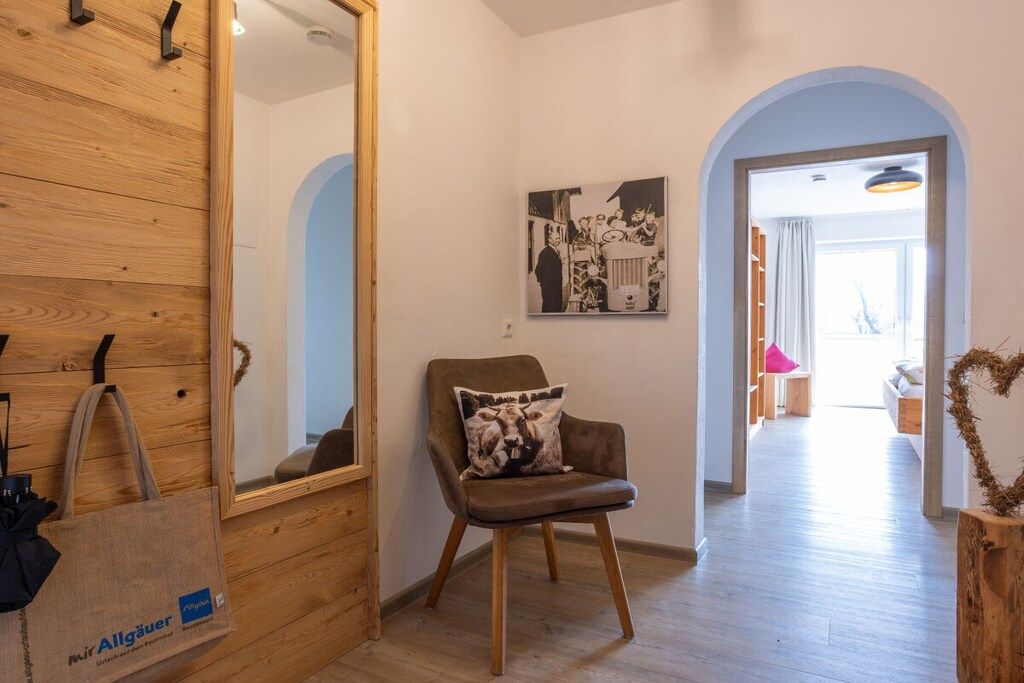Une pièce avec un mur en bois, un fauteuil marron avec un coussin, un miroir et un tableau encadré accroché au mur.