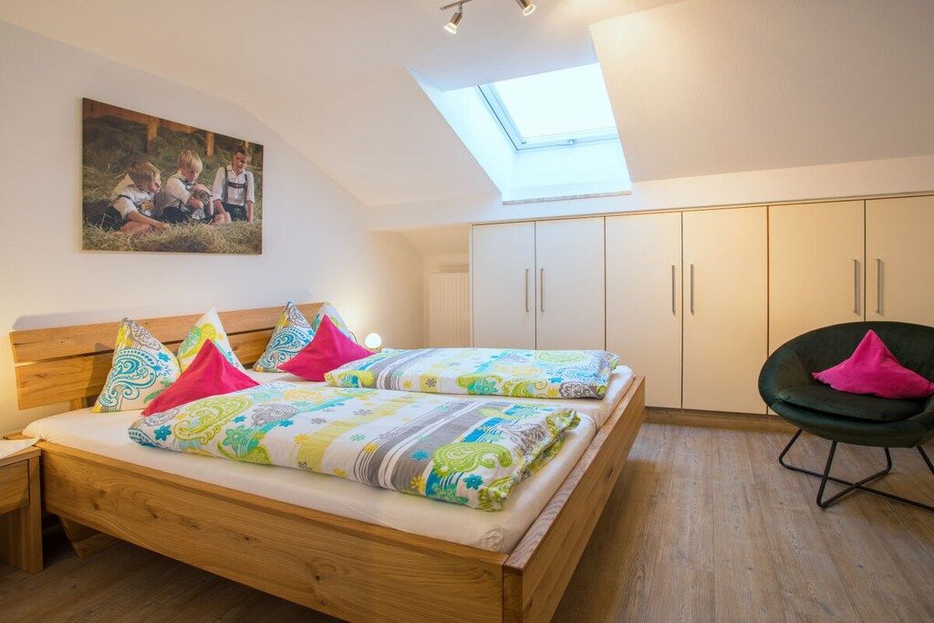 A bedroom with a wooden bed, a skylight, and a painting on the wall.