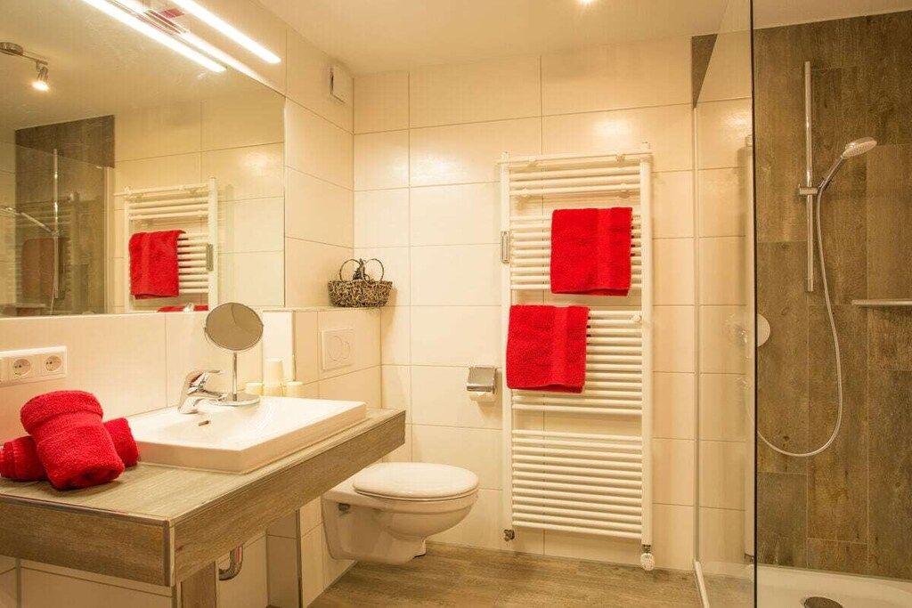 Ein modernes Badezimmer mit Waschbecken, Spiegel, Toilette und Duschbereich.