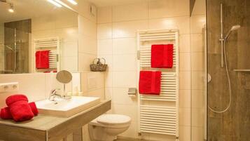 Ein modernes Badezimmer mit Waschbecken, Spiegel, Toilette und Duschbereich.