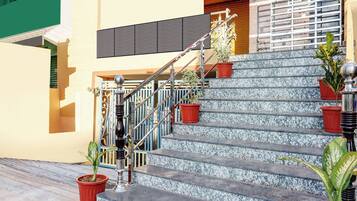A staircase with metal railings, potted plants, and a building facade with a window and a door.
