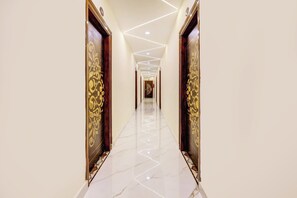 A corridor with a polished marble floor, ornate doors, and recessed lighting.