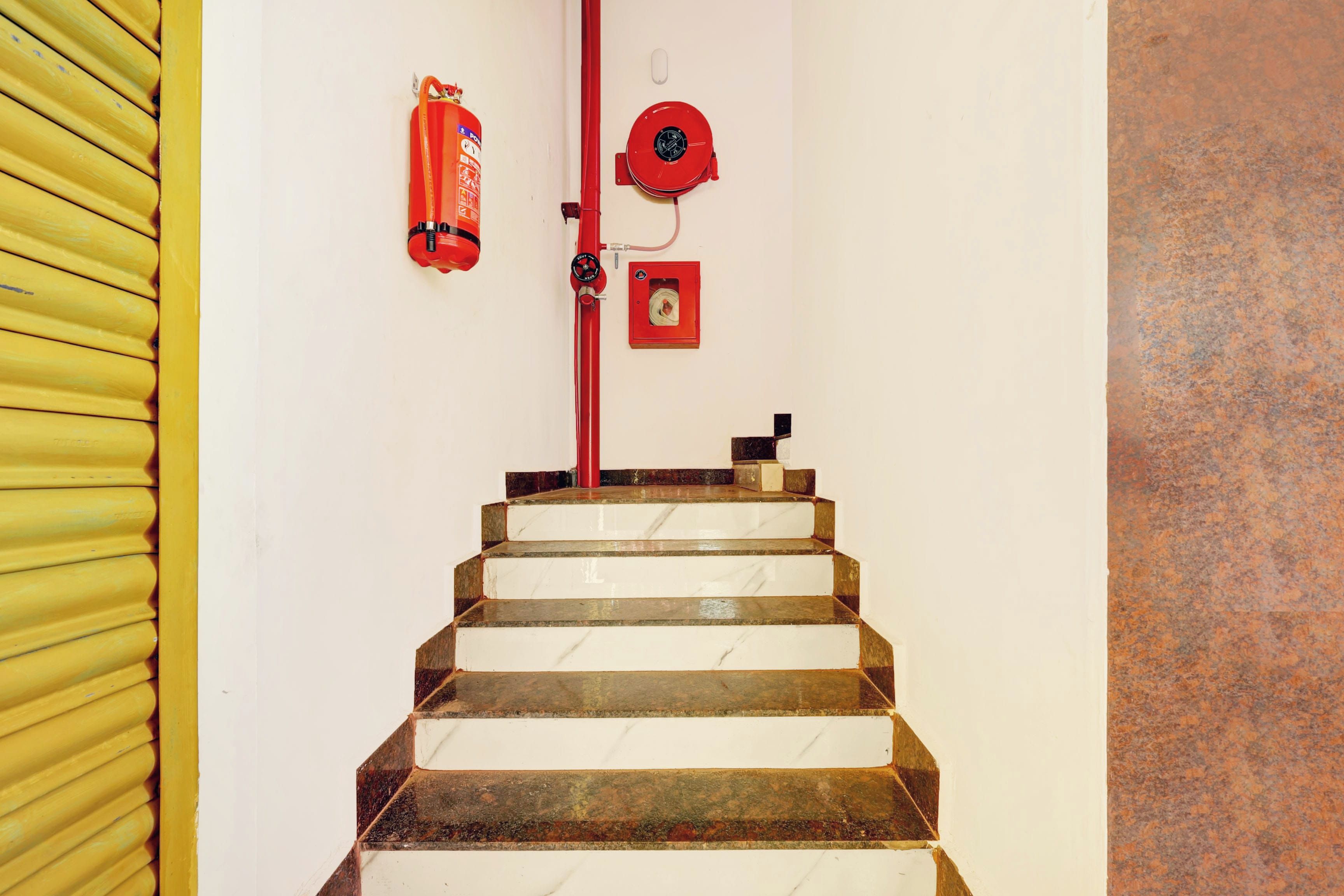 A staircase with a fire hose reel and a fire extinguisher mounted on the wall.