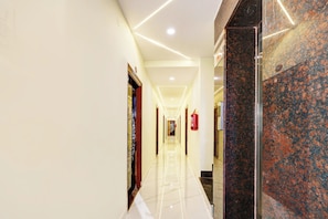A hotel corridor with a polished floor, a fire extinguisher, and a marble wall. - Super Hotel O Vizianagaram (Vizianagaram)