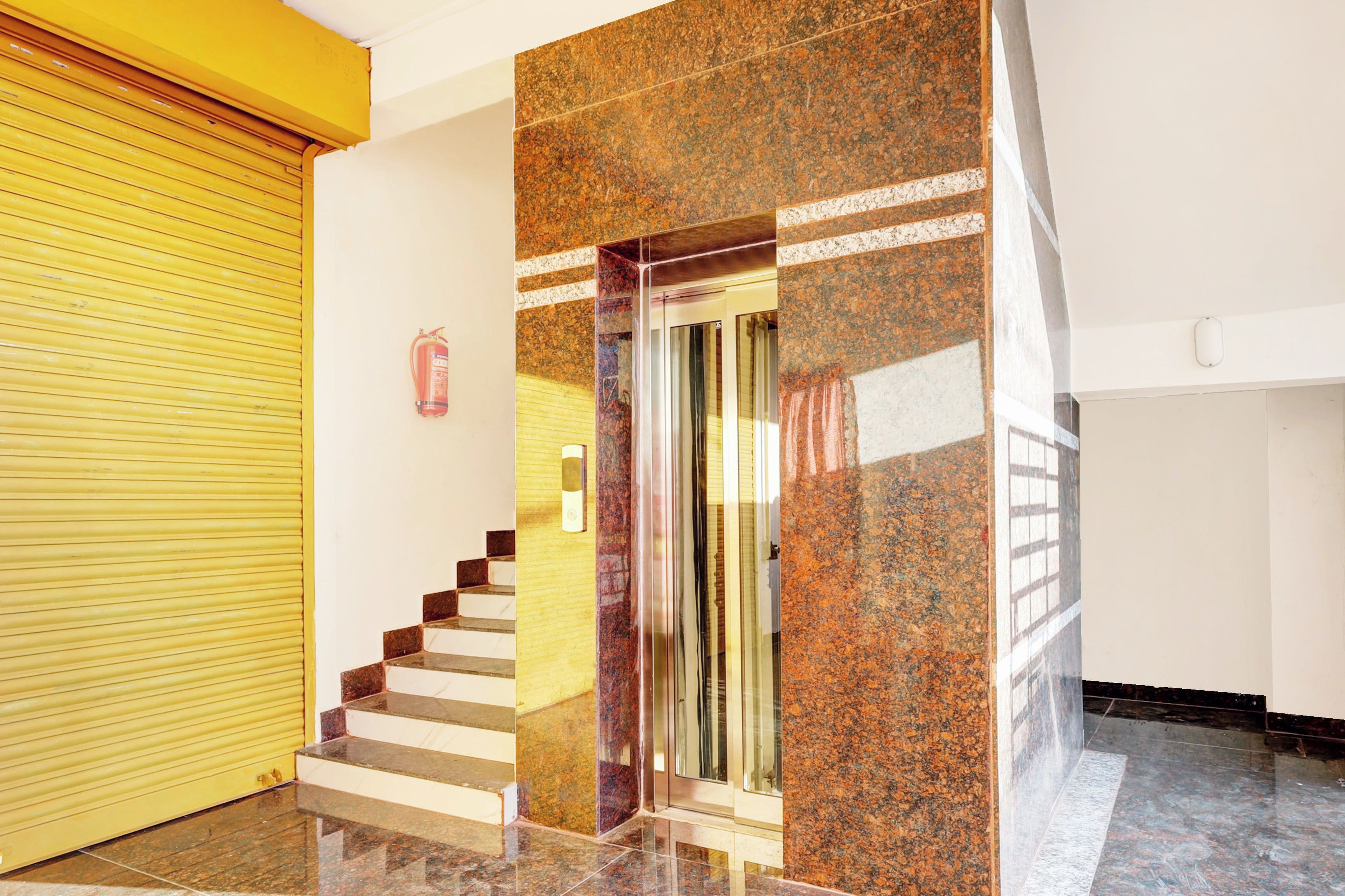 A staircase with a handrail, a fire extinguisher mounted on the wall, and a yellow sliding door.