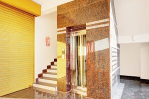 A staircase with a handrail, a fire extinguisher mounted on the wall, and a yellow sliding door.