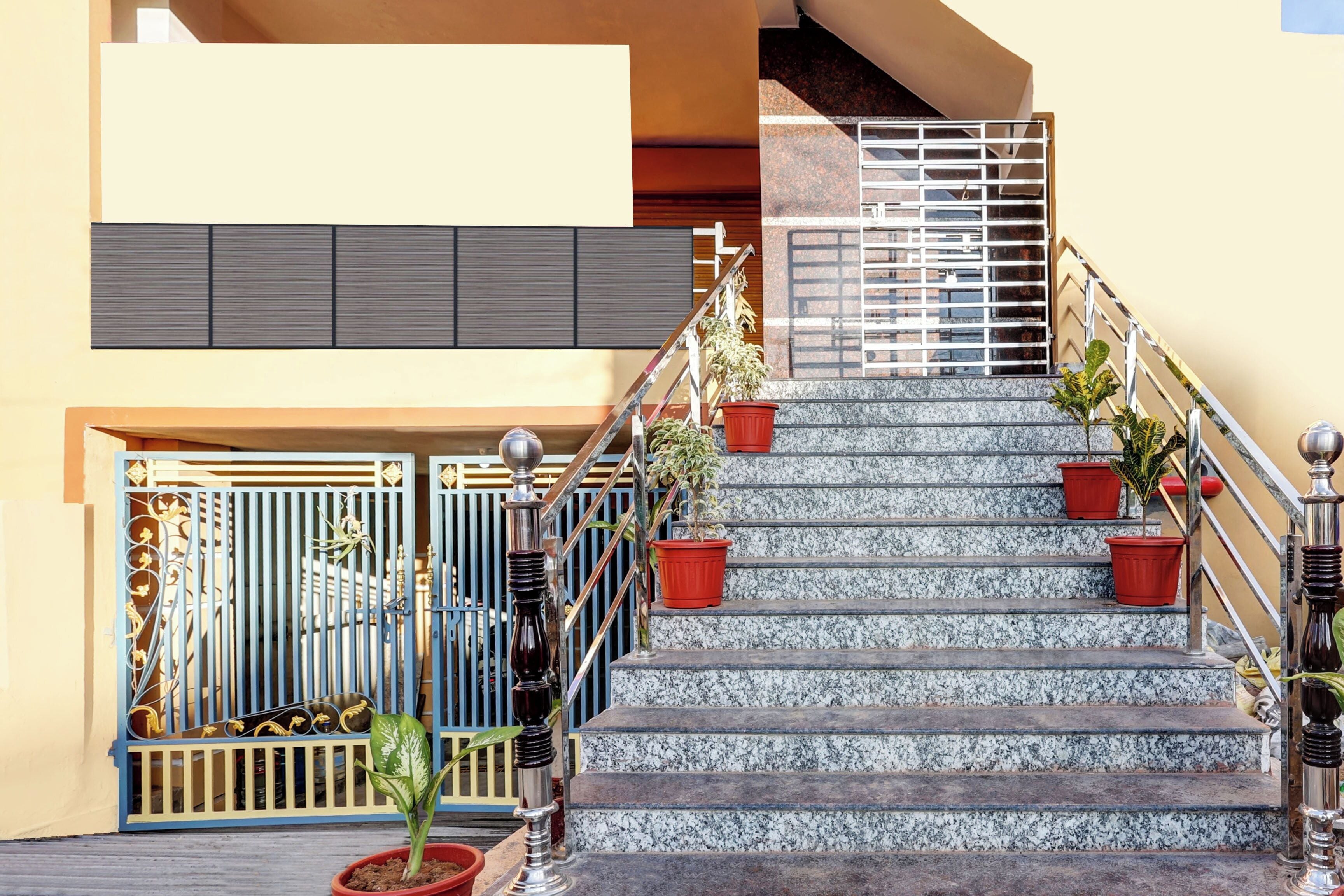 A staircase with a metal railing, potted plants, and a gated entrance.