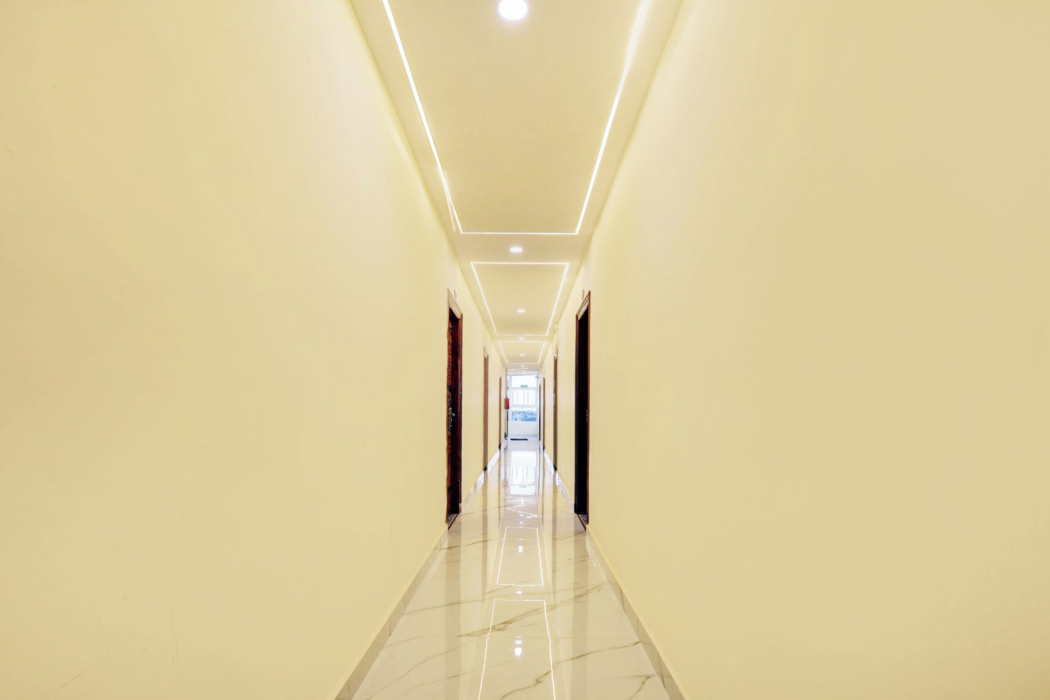 Un pasillo largo y estrecho con piso brillante e iluminación empotrada.