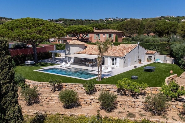 Una propiedad residencial con piscina, zona de estar al aire libre y un muro de contención de piedra.