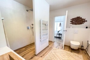Un baño moderno con ducha, inodoro y un tapete estampado.