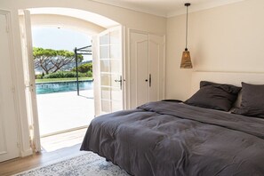 Un dormitorio con cama, una puerta que da a una piscina y una lámpara colgante.