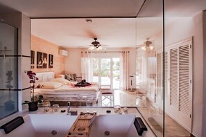 A modern bedroom with a bed, bedside tables, a ceiling fan, and a view through a glass door to an outdoor area. - Villa in Cala Muarad with swimming pool (Cala Muarad)