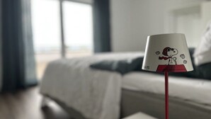 Een hotelkamer met een bed, een raam en een Snoopy lamp.